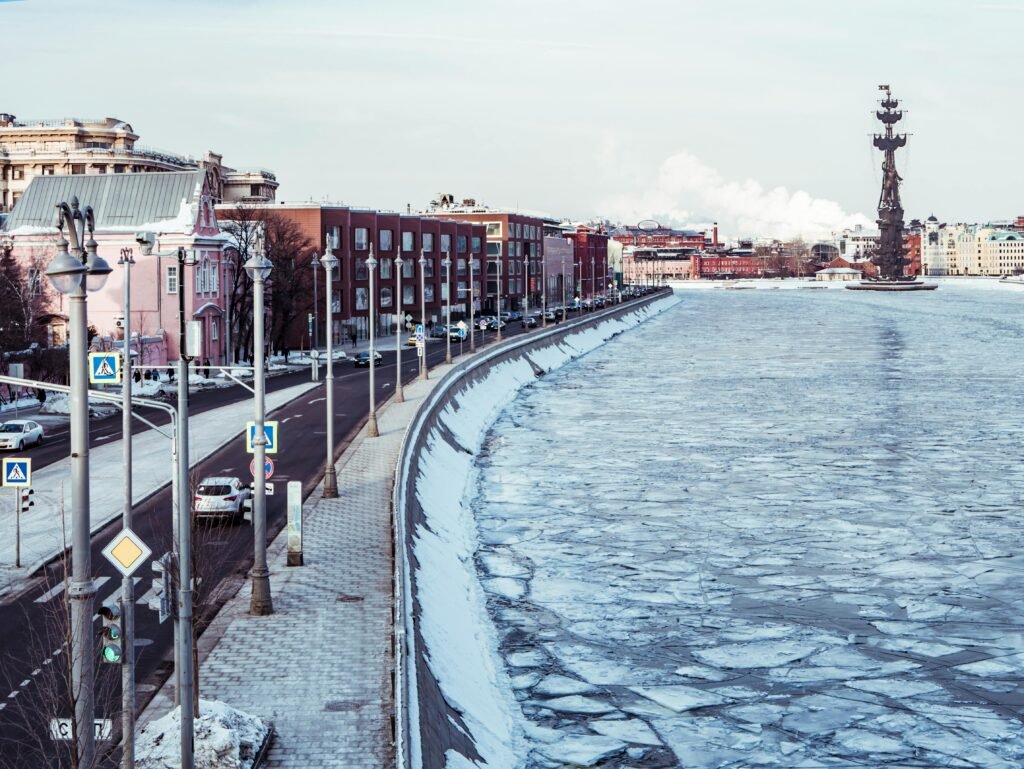 A cityscape features a frozen river and prominent monument in winter.