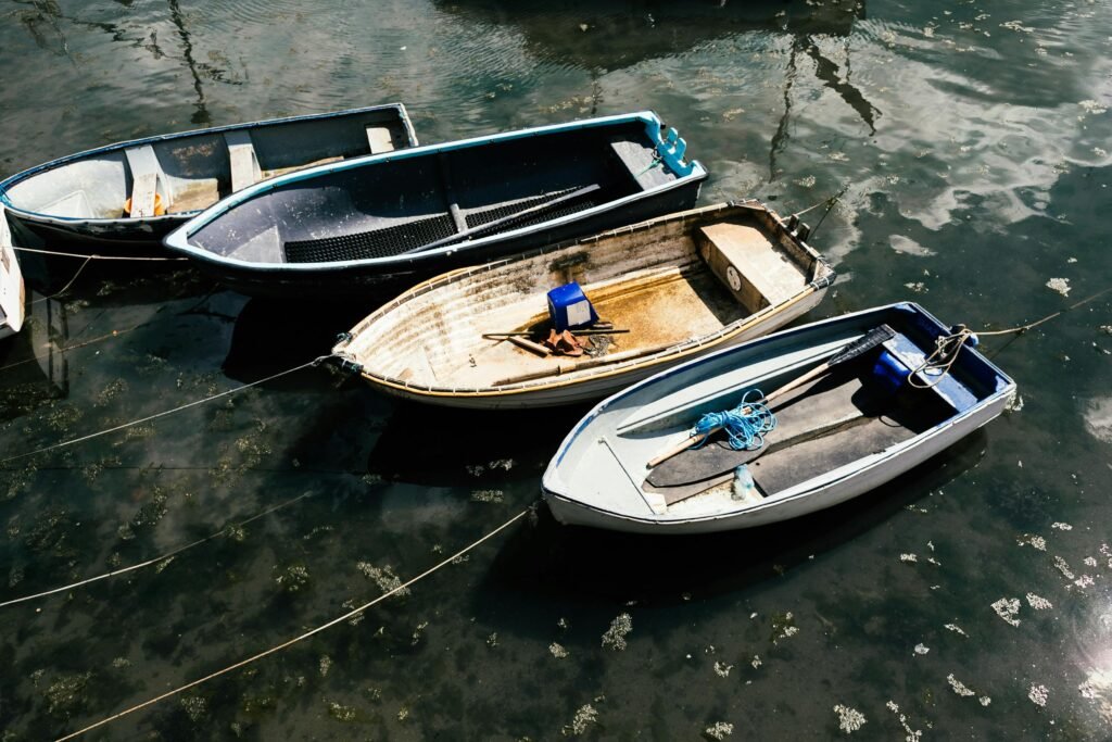 From above of small simple boats moored to coast of glistening river in daylight