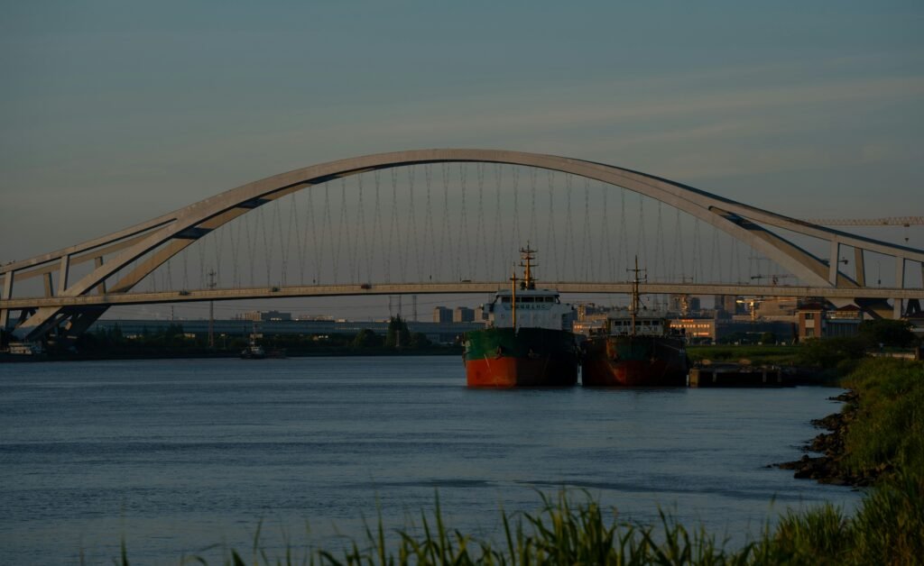 Ships docked near Mingzhou Great Bridge during dusk in Ningbo, China. Tranquil water scene.