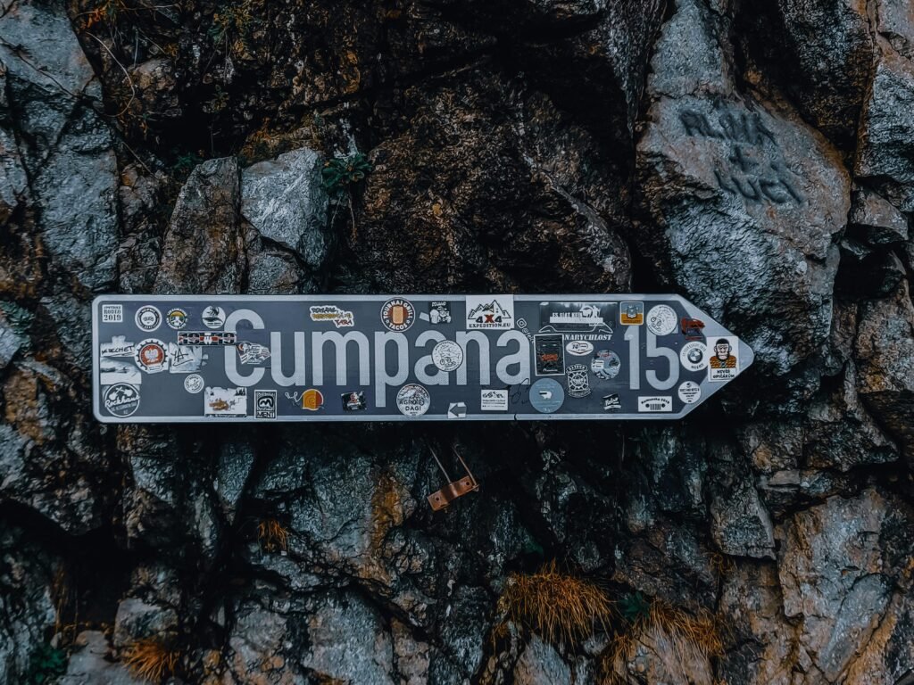 Rough rocky cliff slope with blue arrow sign with inscription in Romanian language guiding to right